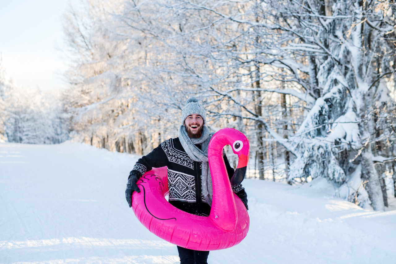 A portrait of young man outdoors in snow in winter forest, having fun.