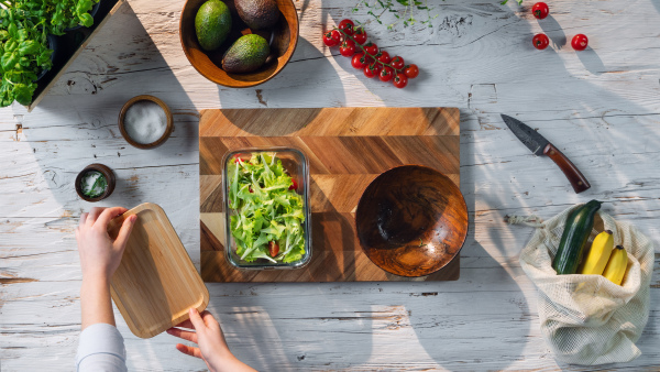 A top view of unrecognizable woman preparing vegetable salad, sustainable lifestyle.
