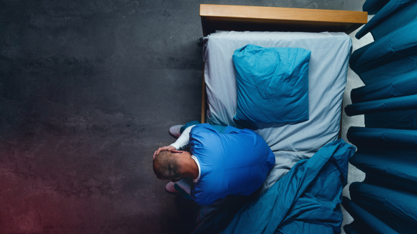 Top view of frustrated doctor sitting on bed in hospital, coronavirus concept. Copy space.