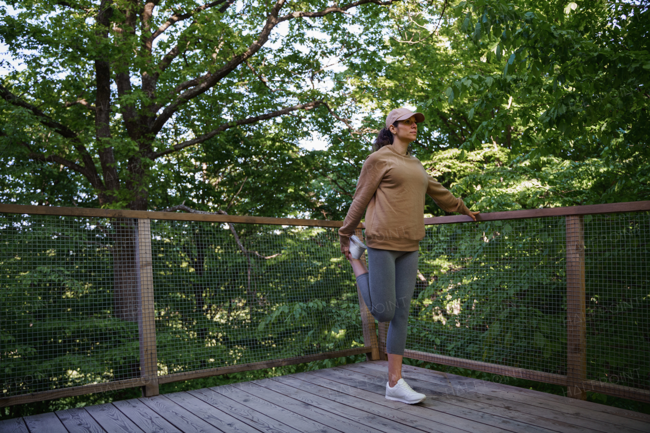 A mid adult woman doing exercise outdoors on terrace of tree house, weekend away and digital detox.