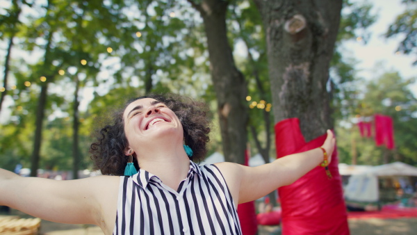A front view of beautiful young woman at summer festival, outstretching arms.
