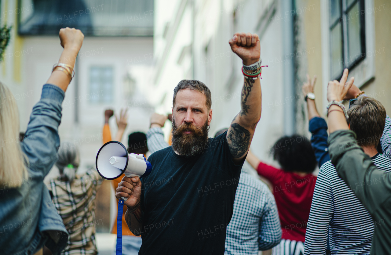 Front view portrait of man with megaphone protesting on streets, strike and demonstration concept.
