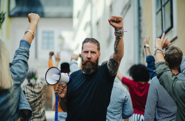 Front view portrait of man with megaphone protesting on streets, strike and demonstration concept.