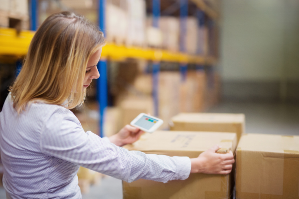 Young woman warehouse worker or supervisor with smartphone.