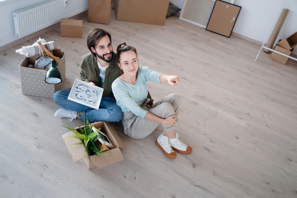 Happy young couple with boxes moving in new flat, new home and relocation concept.