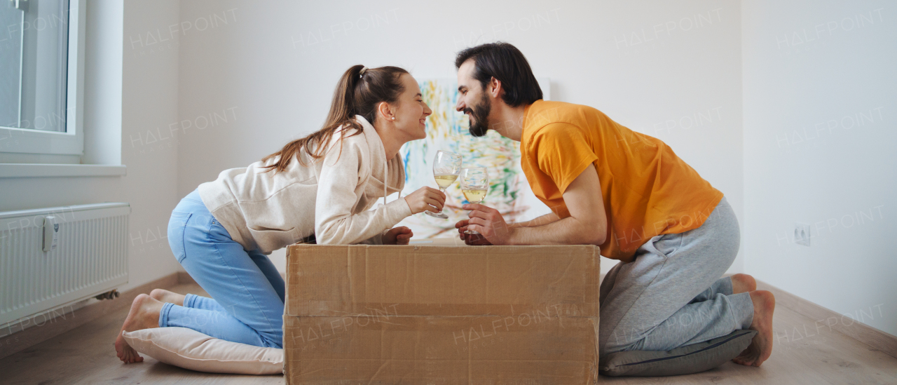 Happy young couple with boxes and wine moving in new flat, new home and relocation concept.