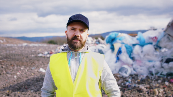 Front view of worker looking at camera on landfill, waste management and environmental concept.