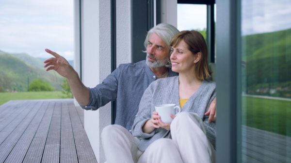 A beautiful couple at home, sitting on terrace and talking together.