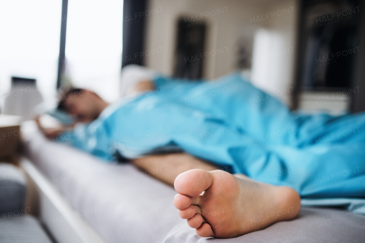 Young man sleeping in bed at home, a close-up of bare foot.