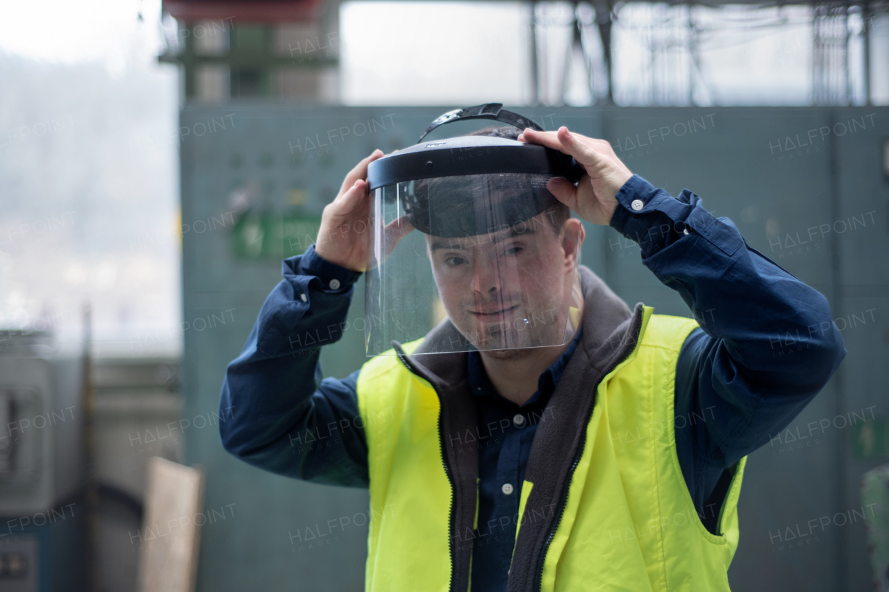 A young man welder with Down syndrome working in industrial factory, social integration concept.