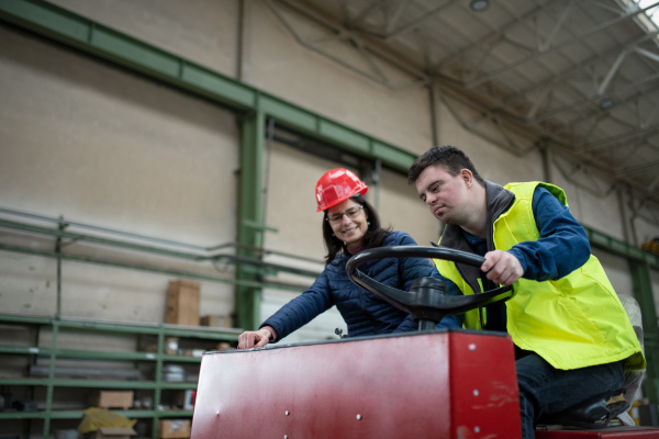 A young man with Down syndrome working in industrial factory, social integration concept.