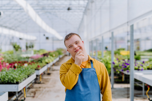 A young employee with Down syndrome working in garden centre, looking at camera.