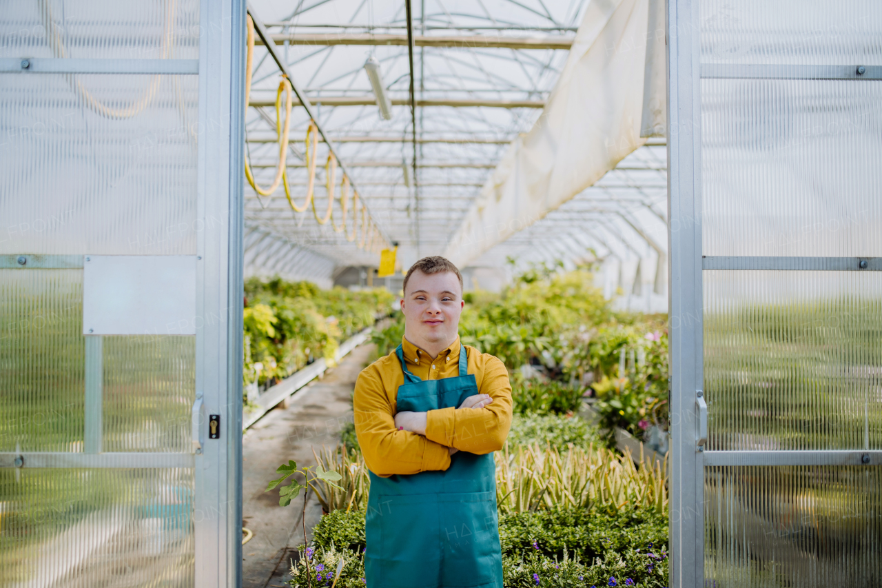 A young employee with Down syndrome working in garden centre, looking at camera.