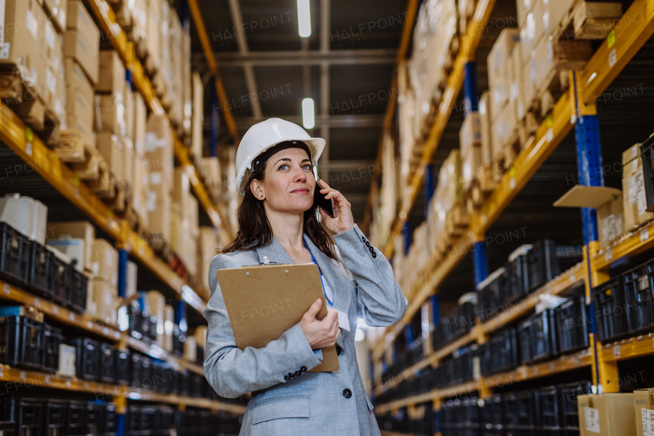 Manager woman in suit calling in warehouse.