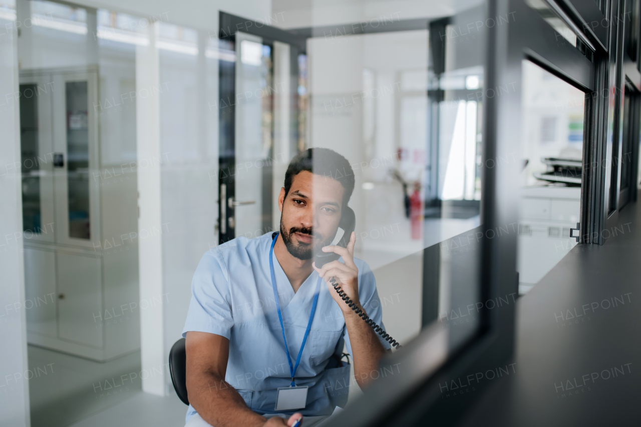 Young multiracial nurse sitting at reception and calling.
