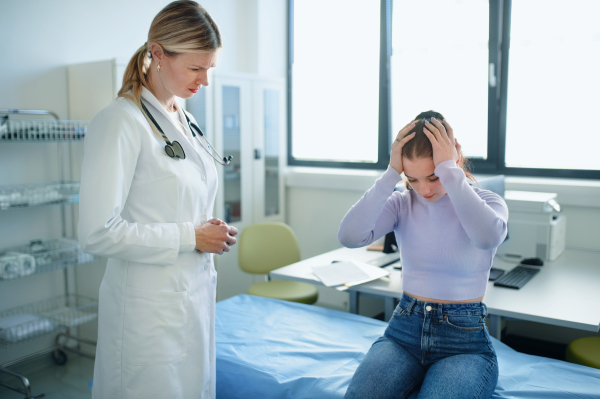 Young woman doctor talking with unhappy teenage girl in the ambulance.