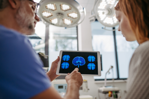 Doctor showing girl teenage patient MRI scan on tablet, discussing test result in emergency room.