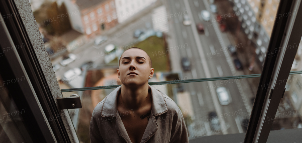 Top view of young unhappy woman with cancer sitting in window.