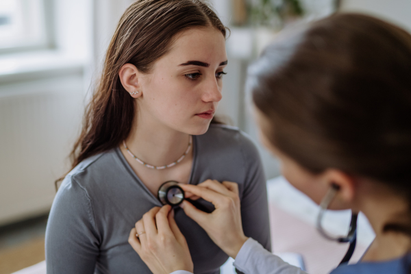 Young doctor examining a teenage girl in her office.