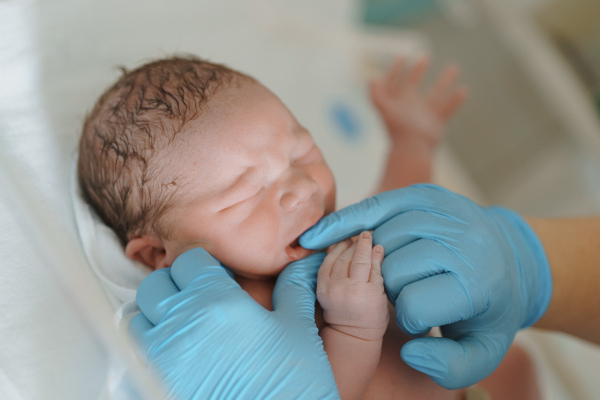 Neonatal nursers, doctor examining mouth of newborn baby, taking care of infant after birth. Neonatal care, newborn's health and well-being.