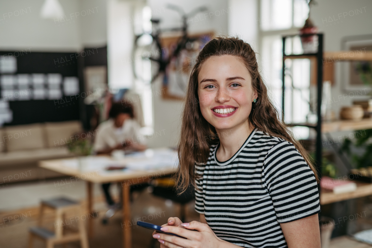 Young woman having break at work, scrolling her smartphone.