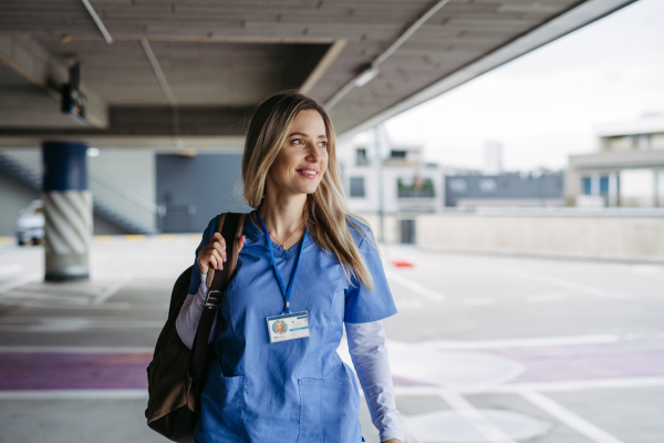 Female nurse, doctor walking across hospital parking lot, going home from work. Work-life balance of healthcare worker.