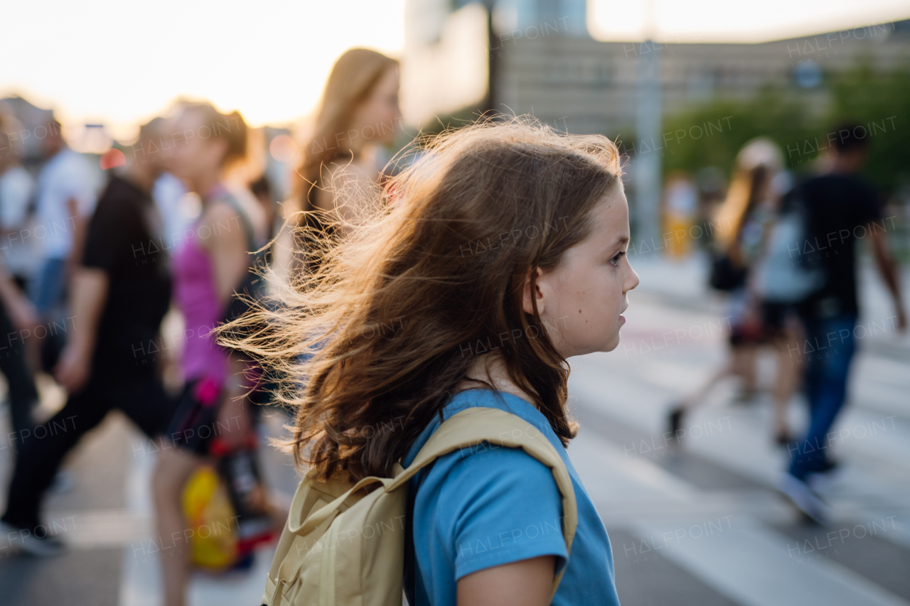 Side view of a girl with a backpack crossing the pedestrian crosswalk on her way to school. Concept of back to school.