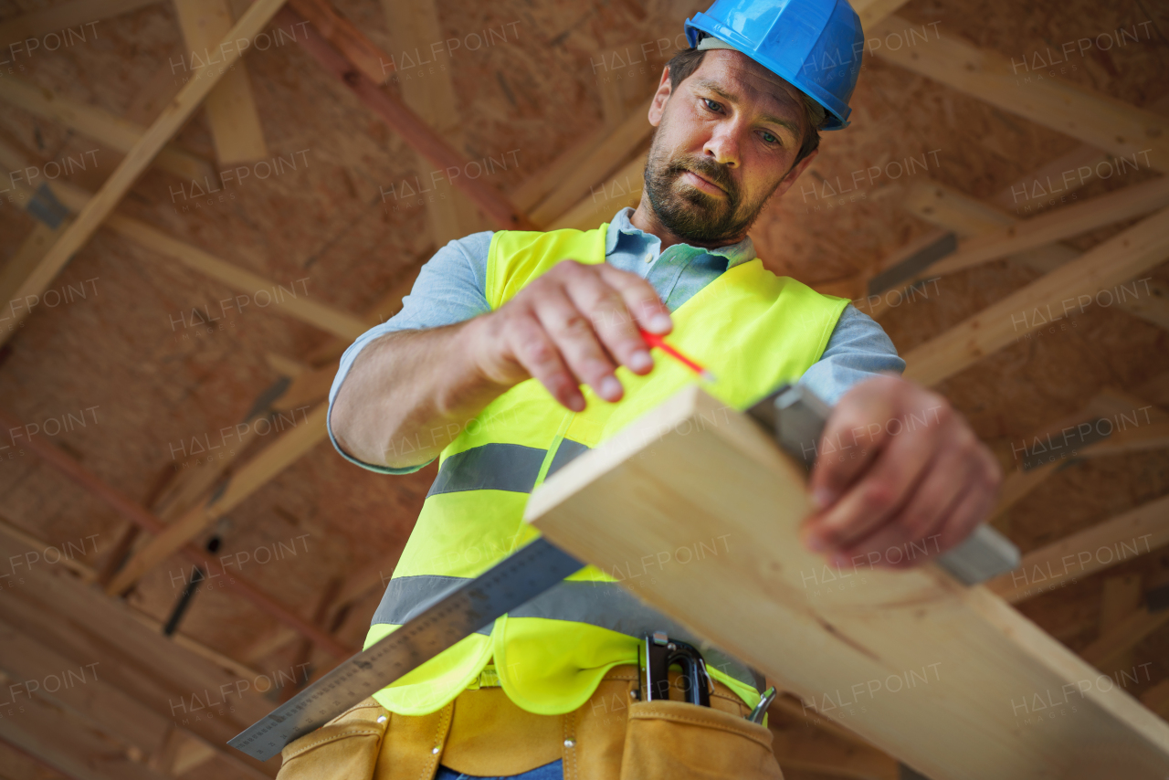 Carpenter measuring wooden planks and making marks with pencil. Carpentry concept.