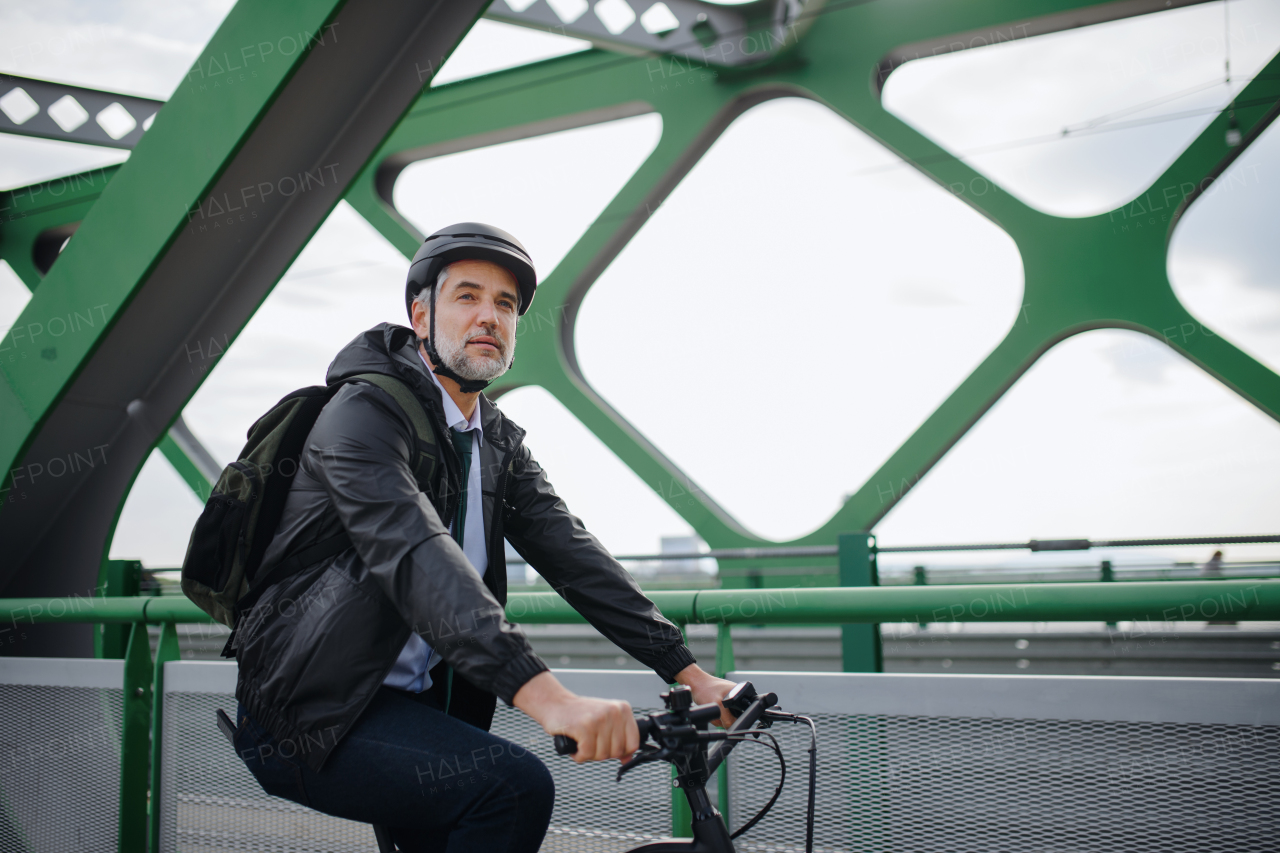 A businessman commuter on the way to work, riding bike over bridge, sustainable lifestyle concept.