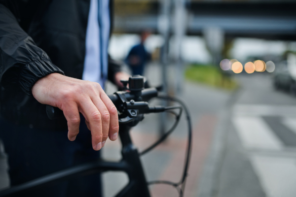 Close-up of businessman commuter on the way to work with bike, holding handles, sustainable lifestyle concept.