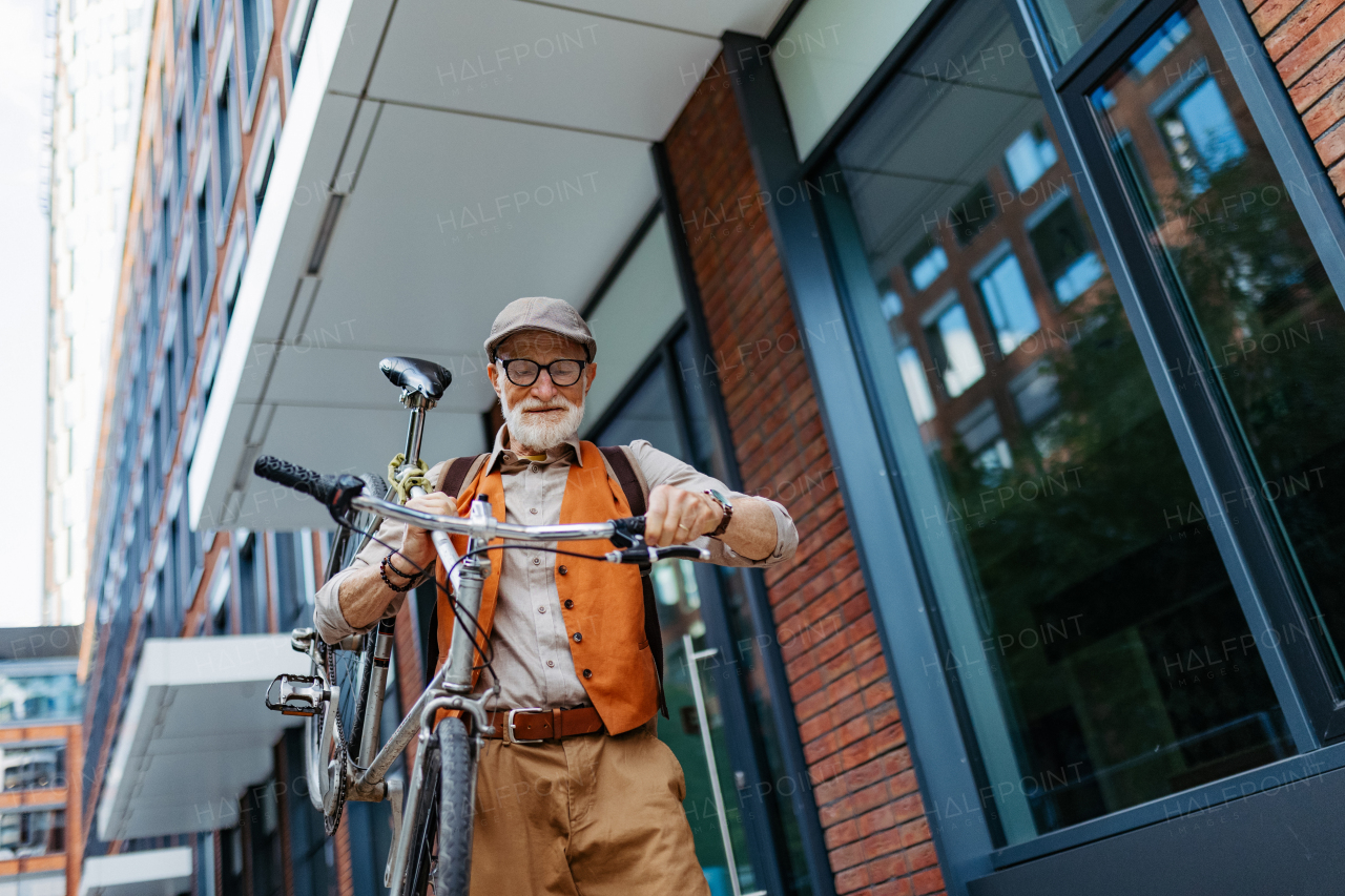 An elderly man, cyclist traveling through the city by bike, carrying bicycle on shoulder. Senior city commuter riding a bike.