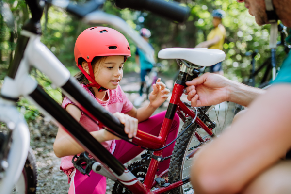 A young family with little children preapring for bike ride, standing with bicycles in nature.