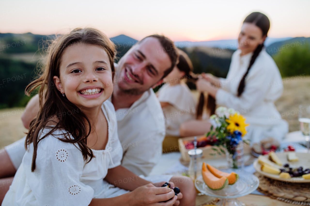 A happy family with children having picnic in park, parents with kids sitting eating healthy meals outdoors.