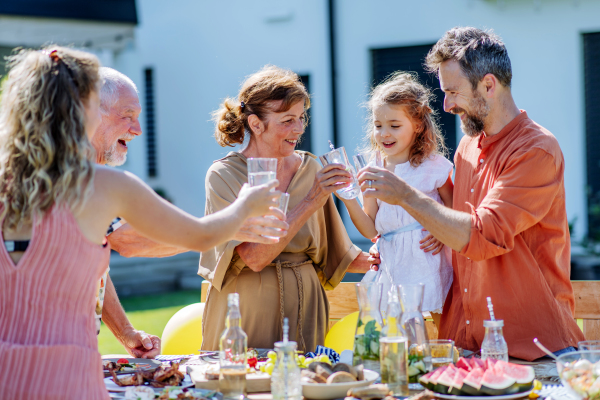 A multi generation family having garden party celebration, toasting and laughing.