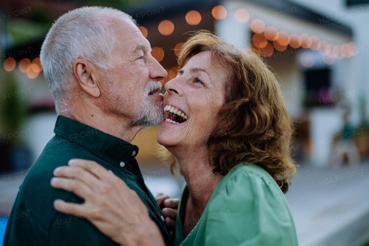 A senior woman and man dancing together in a garden in summer.