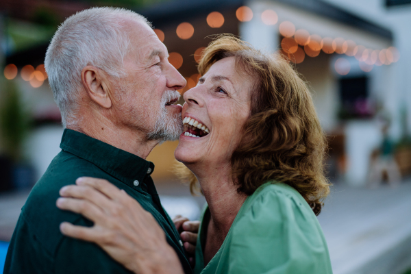 A senior woman and man dancing together in a garden in summer.