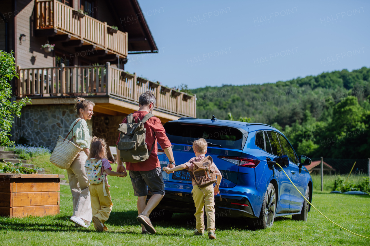 Happy family preparing for trip, charging their electric car.