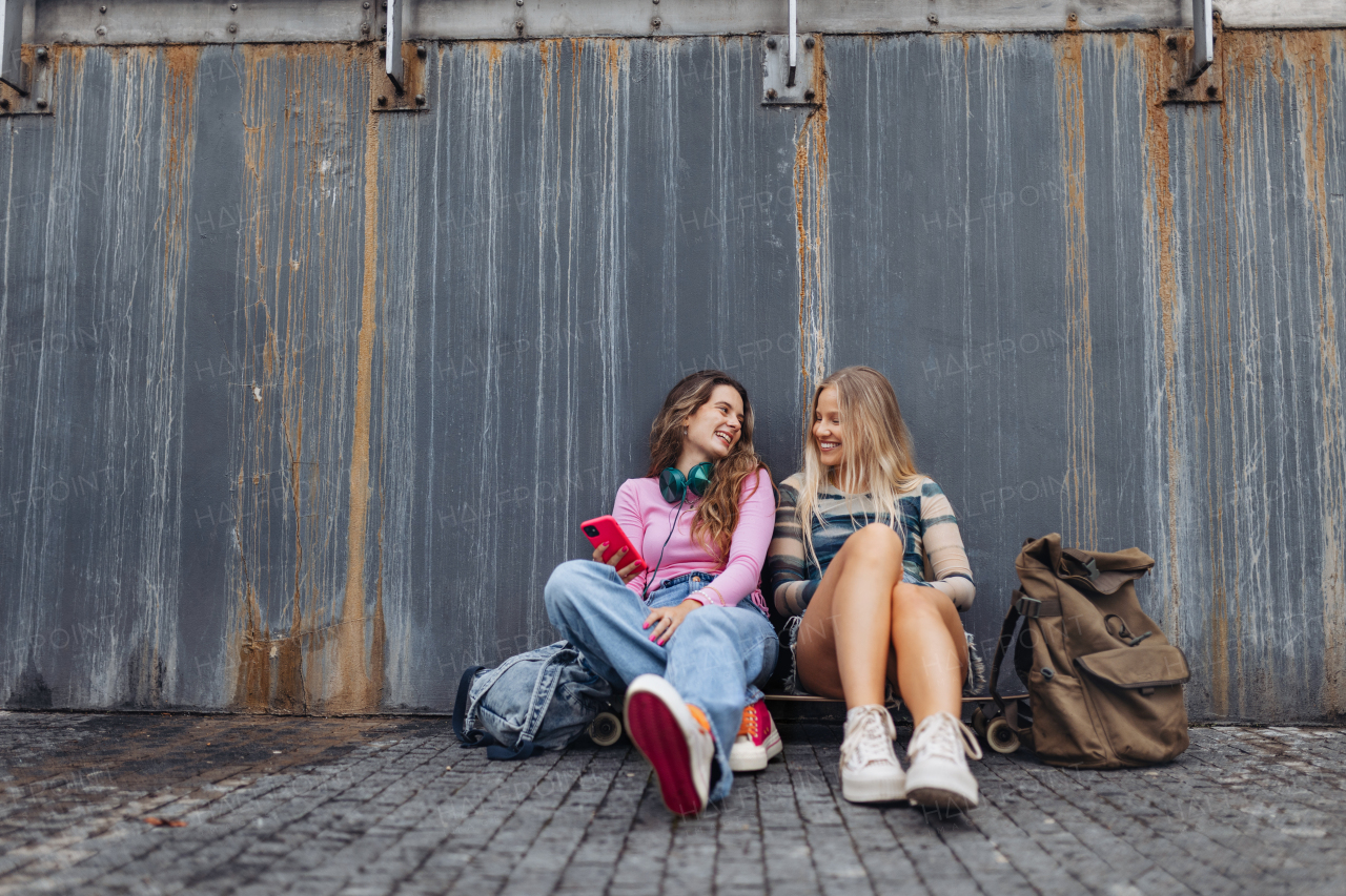 Young stylish generation Z girls spending time together outdoors after school. Young female zoomers talking and gossiping during lunch break in the school. Concept of power of friendship and importance of education for gen Z.