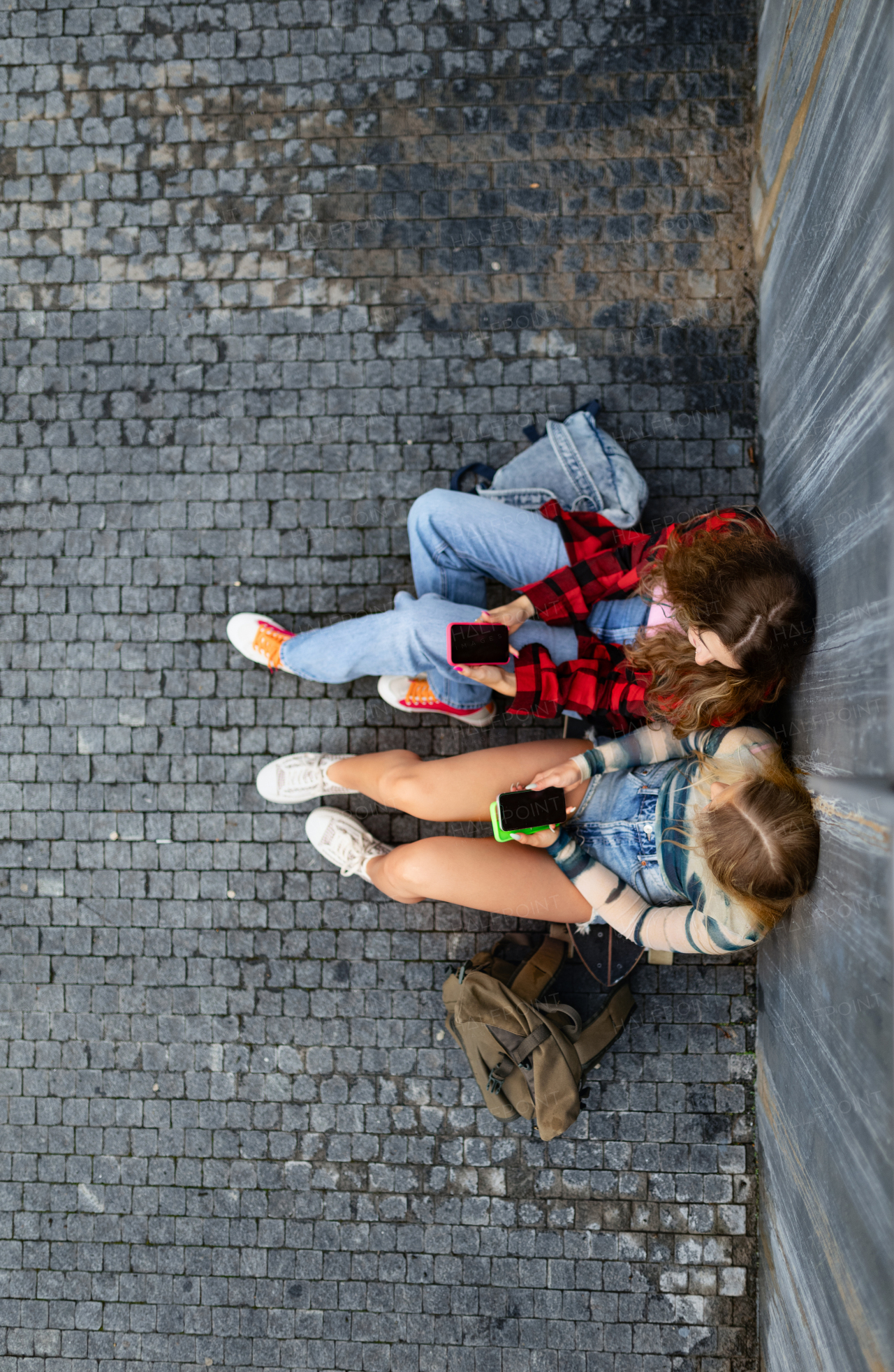 Top view of young stylish generation Z girls studying together outdoors after school. Young female zoomers talking and gossiping during lunch break in the school. Concept of power of friendship and importance of education for gen Z.