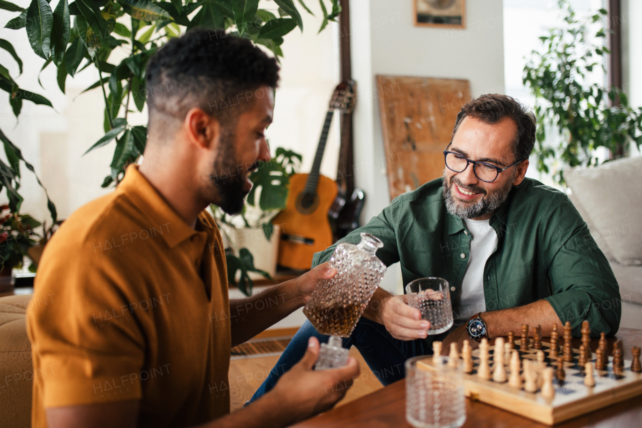 Best friends playing chess together, drinking whiskey and talking. Concept of male friendship and bromance.