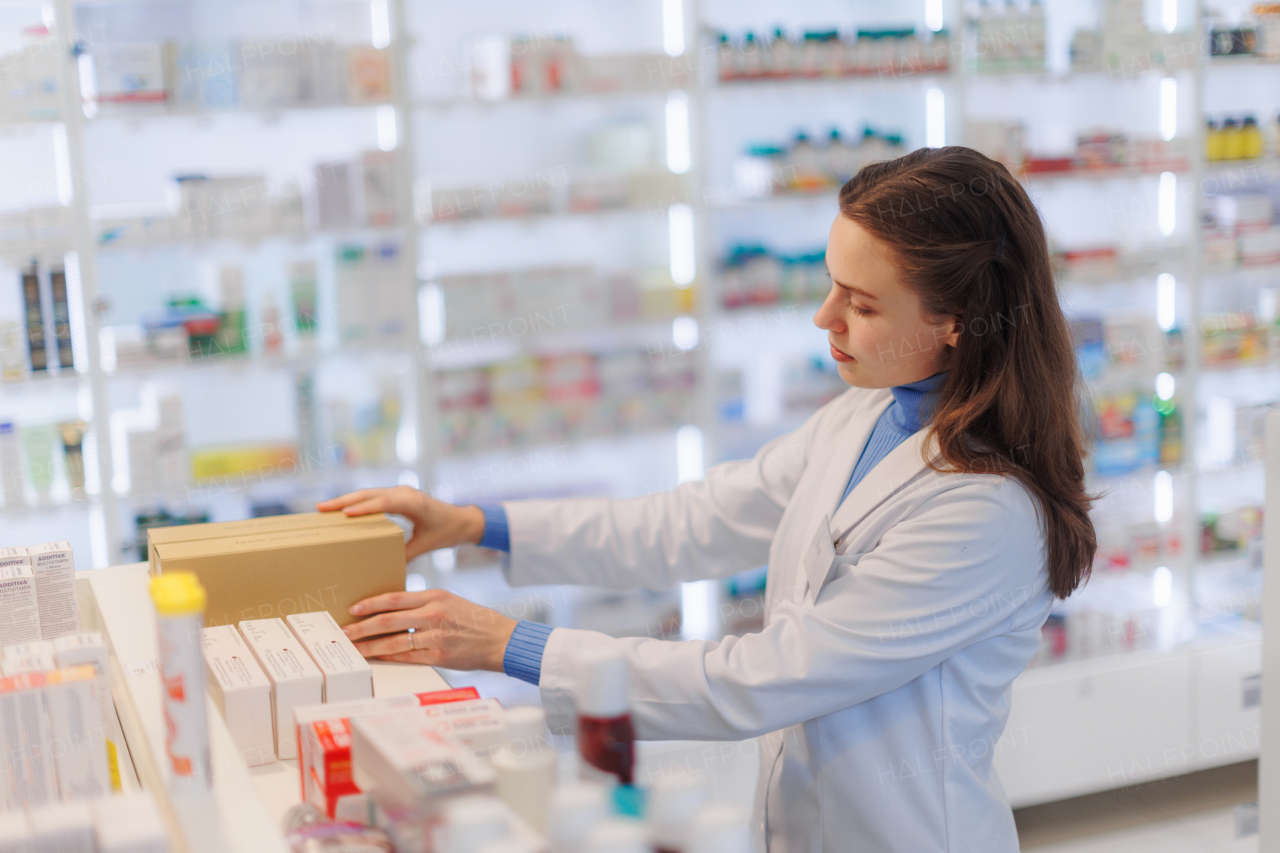 Young pharmacist checking medicine stock in a pharmacy.