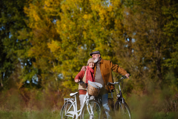 Lovely elderly couple on standing in the middle of forest with their bikes, enjoying peaceful moment together.