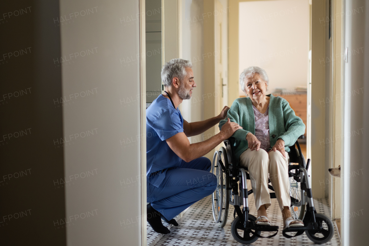 Caregiver doing regular check-up of senior client in her home. Thoughful male nurse taking care of eldery patient on wheelchair.
