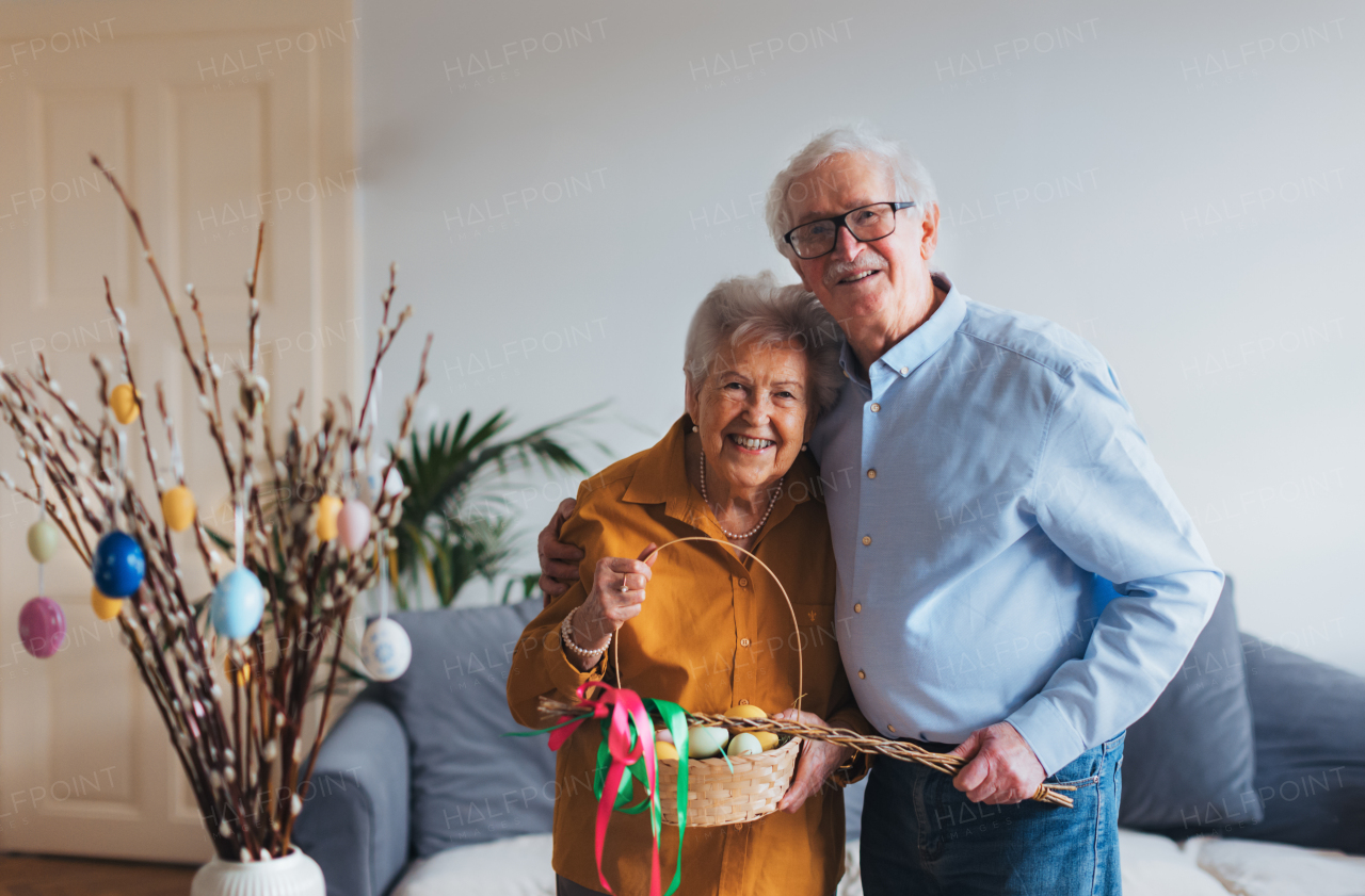Portrait of senior couple holding handmade whip and basket with colored easter eggs. Easter tradition, unique easter custom from slovakia. Easter tradition, whip made of willow branches, decorated with ribbons. Unique easter custom from slovakia.