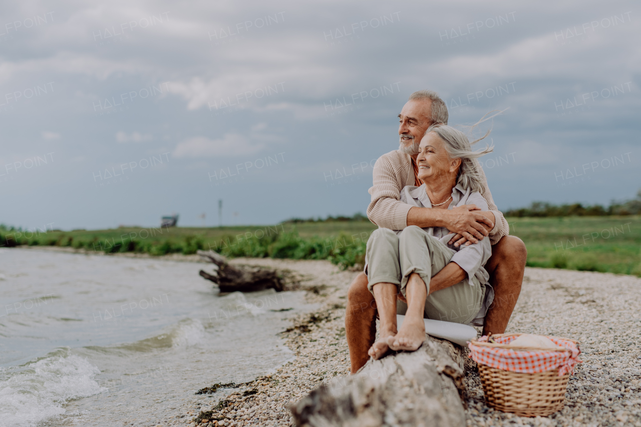 Senior couple sitting and having romantic moment at the autumn sea.