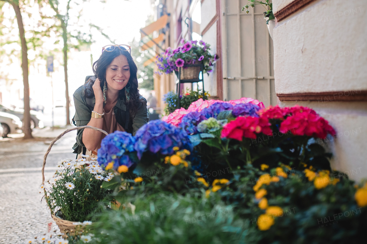 A young urban woman looking at flowers at street shop on sunny day in summer.
