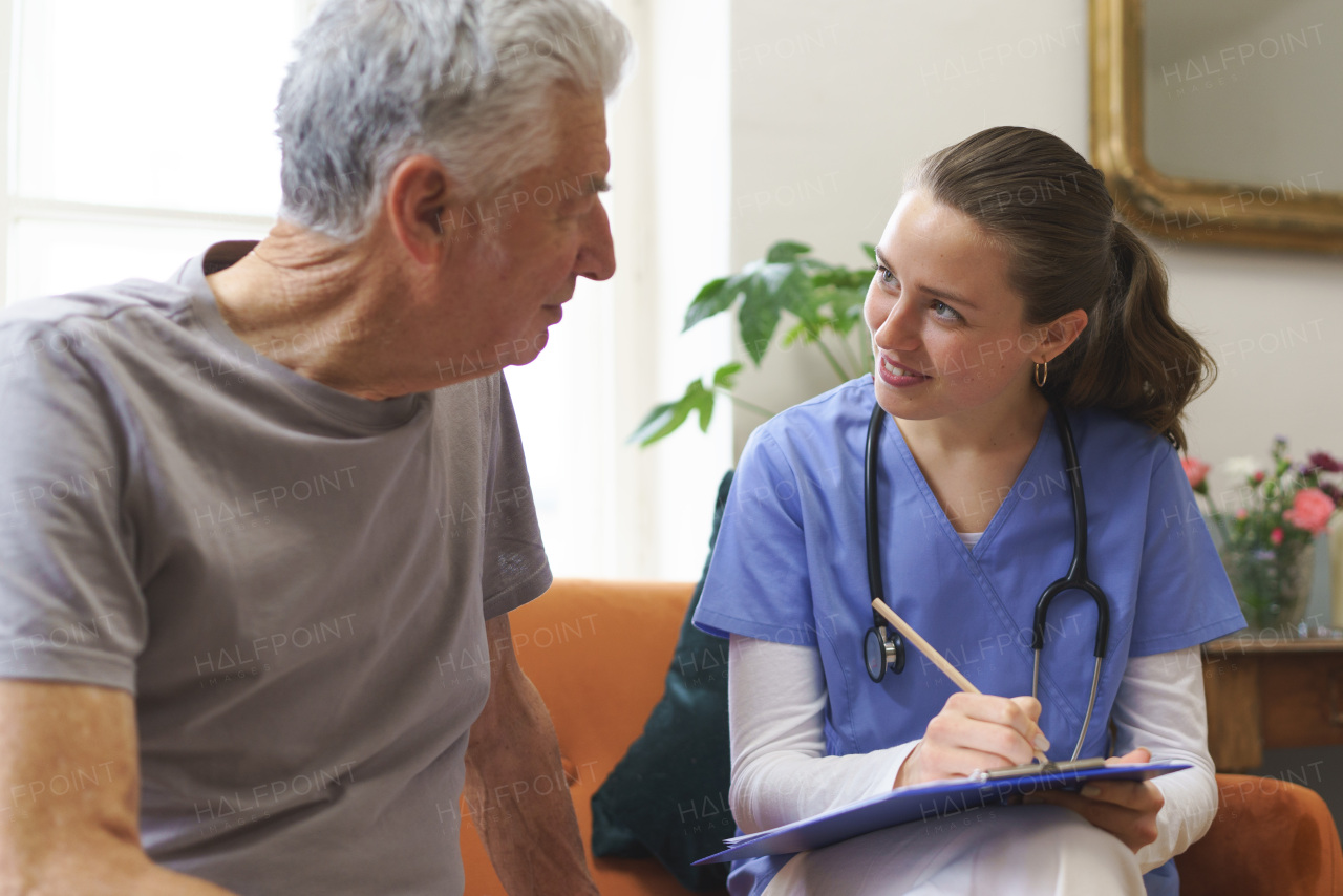 Young nurse taking care of elderly senior in his home.