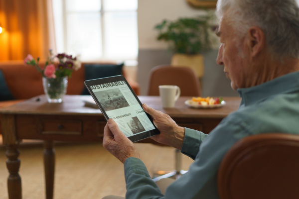 Senior man reading news in a digital tablet.