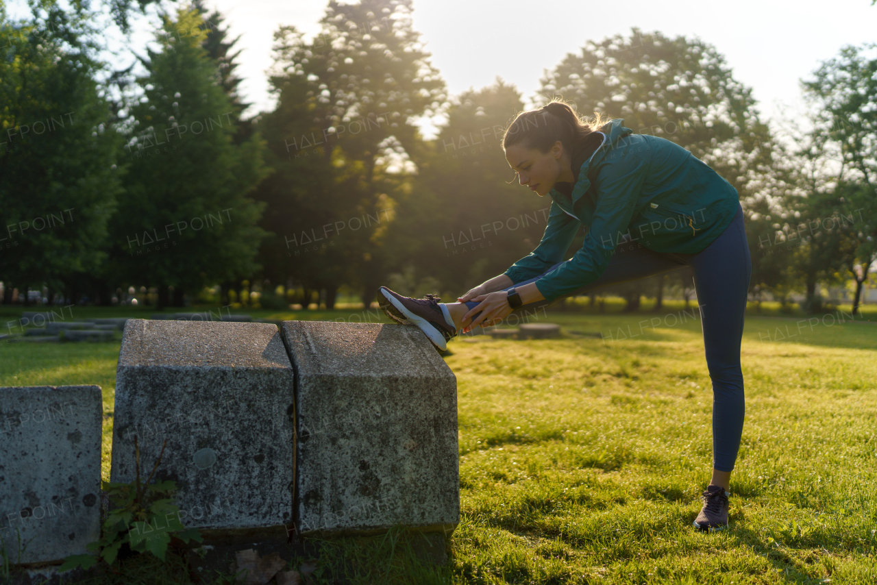 Full lenght portrait of beautiful fitness woman stretching before outdoor workout in the city park. Healthy lifestyle concept. Copy space.