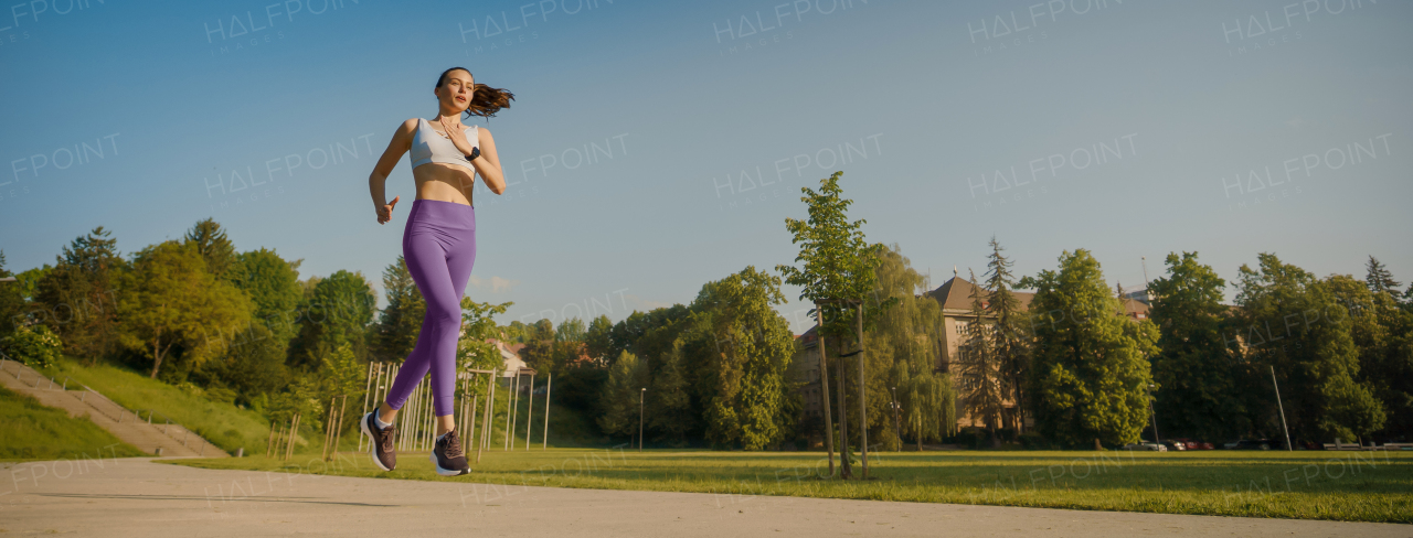 portrait of athletic young woman in activewear running in the city in the morning. Outdoor workout concept. Banner with copy space.